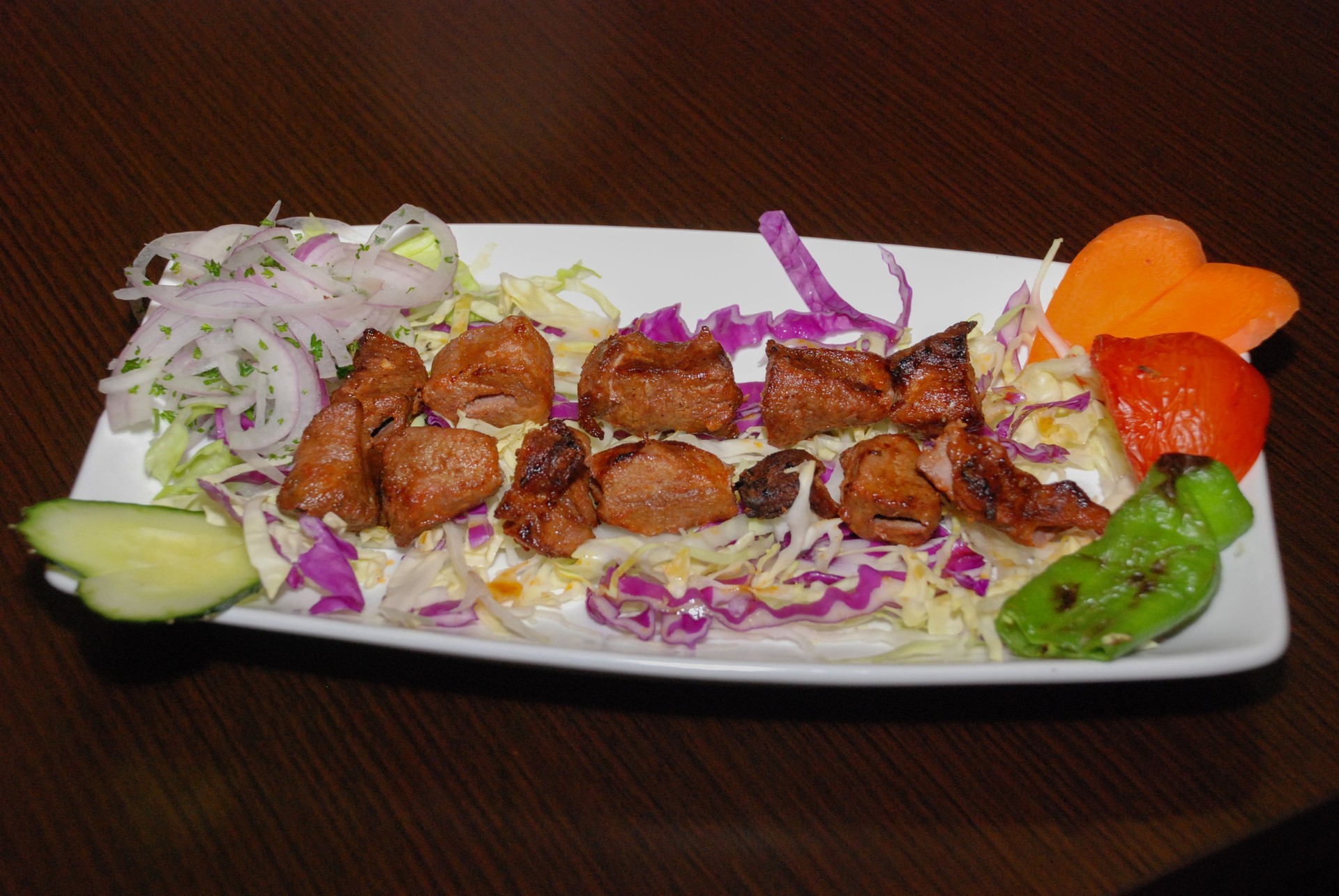 Barbequed lamb meat on the salad with vegetables, served on the white plate